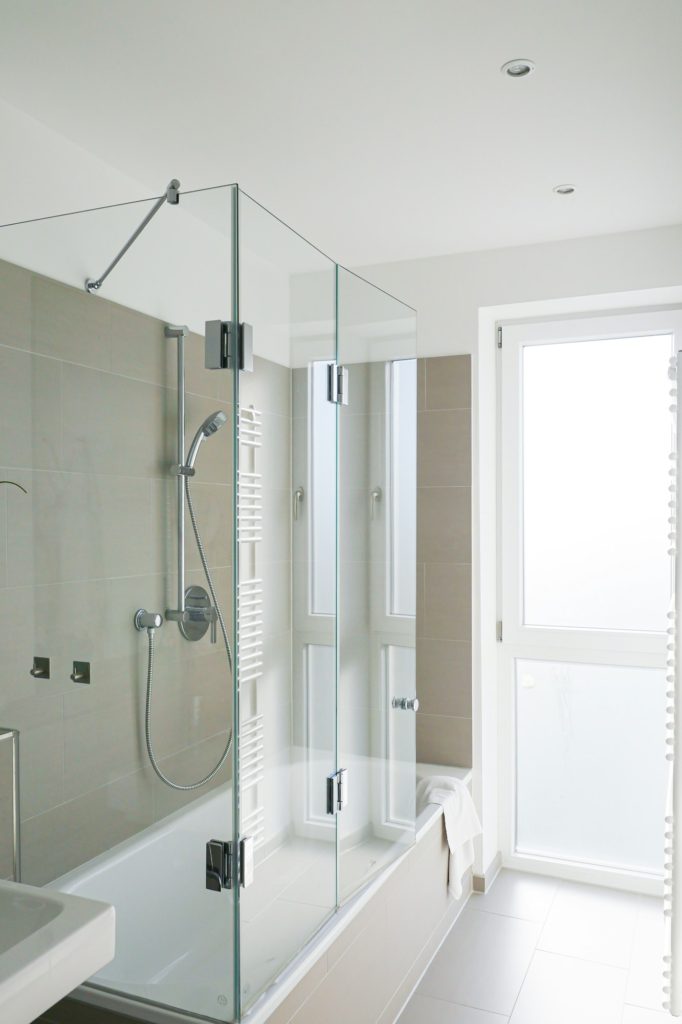 Vertical shot of a modern white bathroom with shower that has glass doors