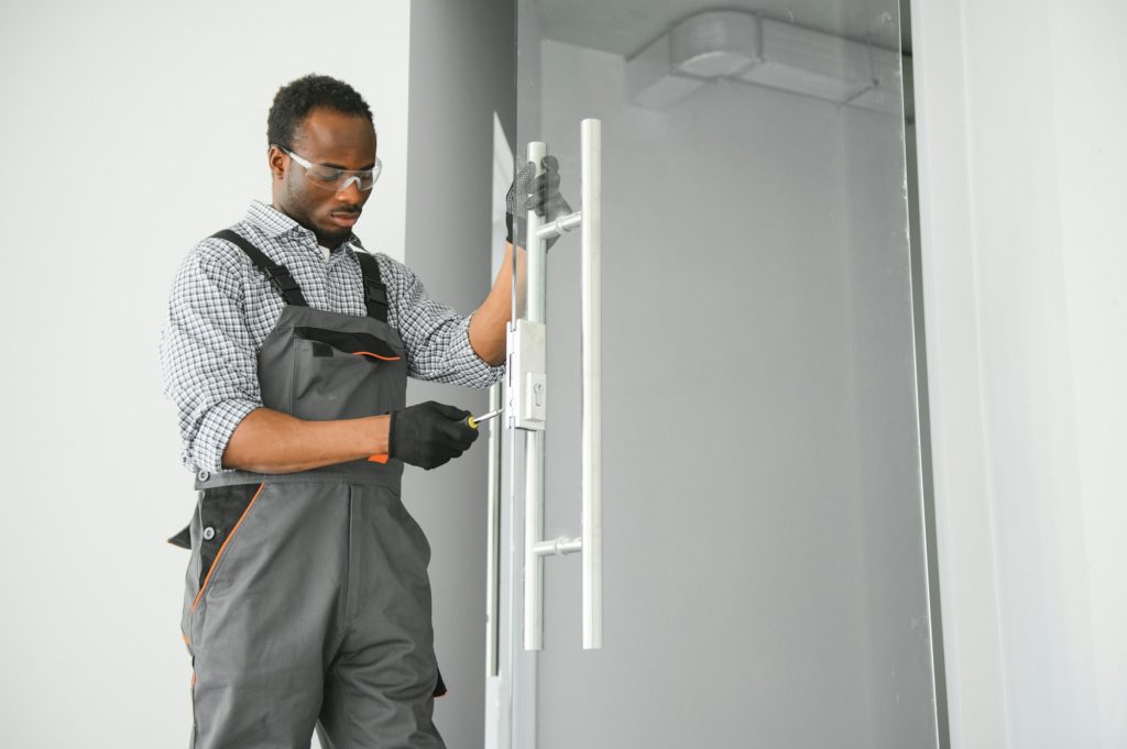 Worker installing glass door at office